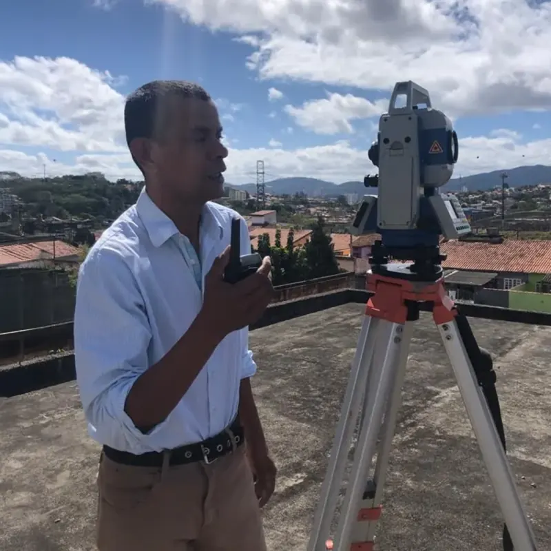 Topógrafo com estação total realizando medição no telhado